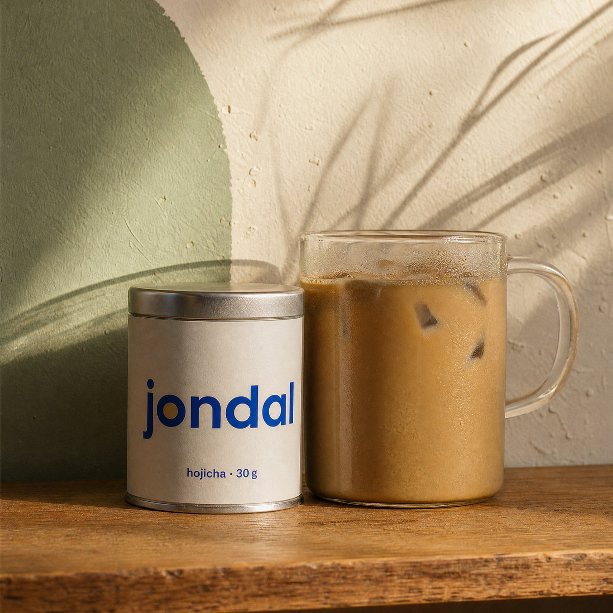 Jondal hojicha tin next to an iced hojicha latte