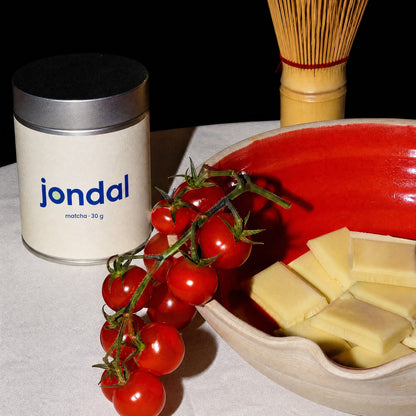Tin of Jondal matcha 30 g on a linen table with cherry tomatoes and a red bowl